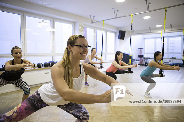 Women in exercise class doing suspension training