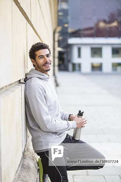 Man in sports clothing leaning against wall in city