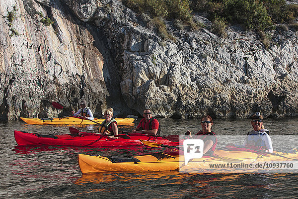 Group of people kayaking next to rock formation
