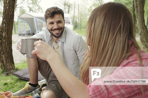 Young couple drinking coffee at campsite