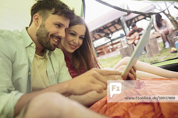 Young couple at campsite using digital tablet