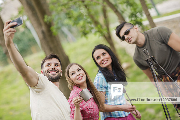 Group of friends taking selfies at campsite