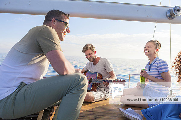Young man playing guitar on sailboat