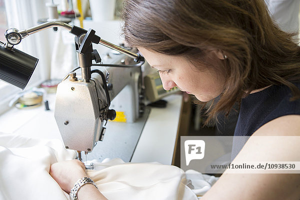 Woman working at sewing machine in bridal shop