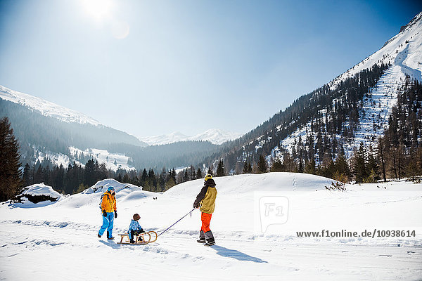 Family pulling sledge with son in Alpine scenery