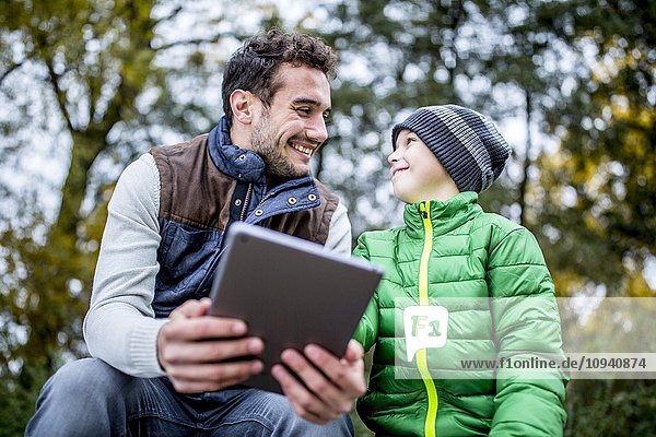 Mann und Junge benutzen digitales Tablet