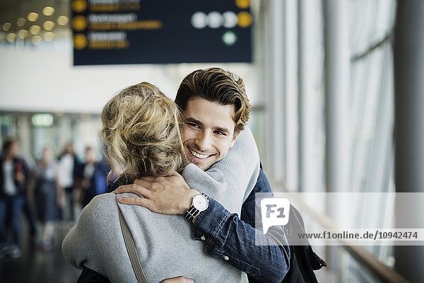 Glücklicher Geschäftsmann umarmt Kollegin am Flughafen