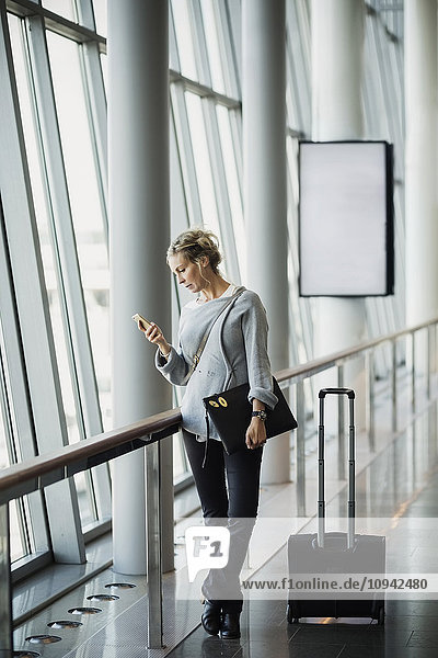 Geschäftsfrau mit Smartphone am Flughafen