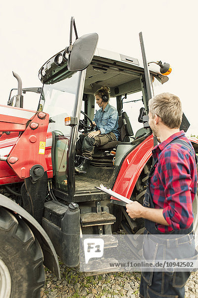 Mann schaut auf Traktorfahrerin in der Landwirtschaft