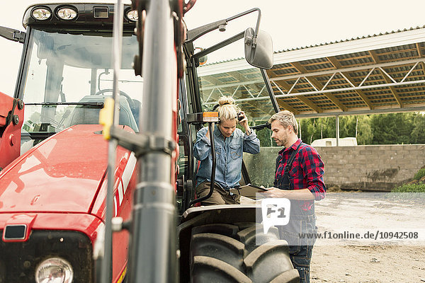 Paar bespricht Dokument mit dem Traktor auf dem Bauernhof