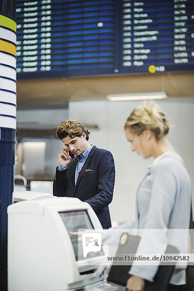 Geschäftsleute mit Check-in-Maschinen am Flughafen