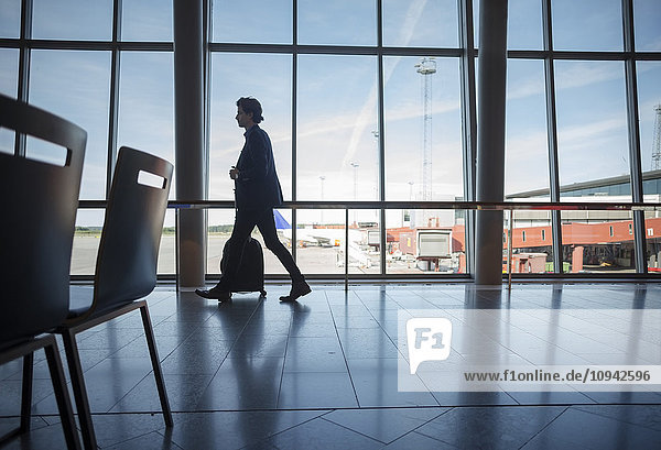 Side view of businessman walking with luggage at airport