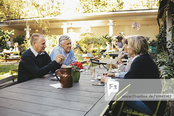 Fröhliche Seniorenpaare diskutieren im Outdoor-Restaurant