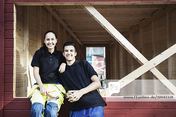 Porträt der glücklichen Schreinerei-Schüler vor der Holzhütte