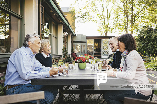 Side view of happy senior couples having food at outdoor restaurant