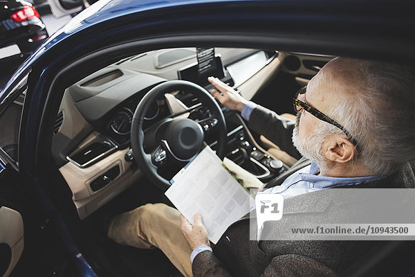 High angle view of senior man examining while sitting in car