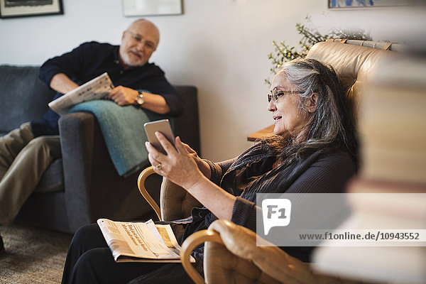 Senior woman showing mobile phone to man at home