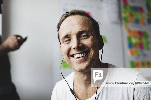Portrait of happy businessman with headphones in creative office