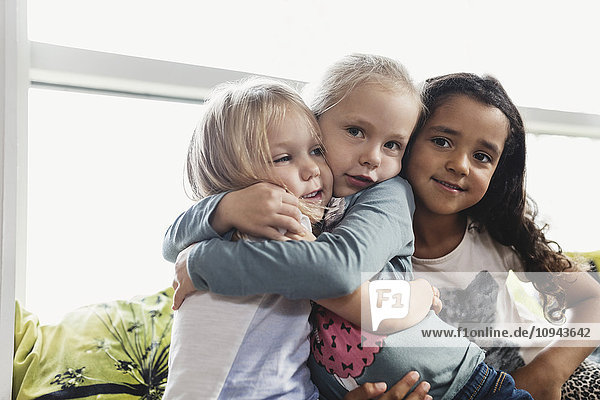 Porträt von Mädchen  die sich in der Kindertagesstätte umarmen