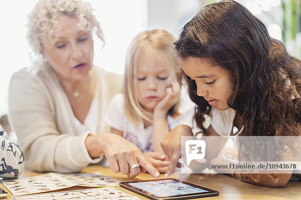 Senior Lehrerin und kleine Mädchen mit digitalem Tablett