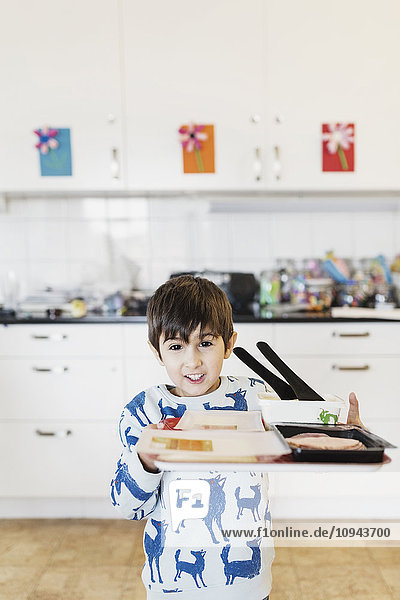 Porträt eines glücklichen Jungen mit Essenstablett