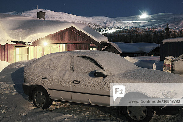 Schneebedeckter Parkplatz vor dem Haus bei Einbruch der Dunkelheit