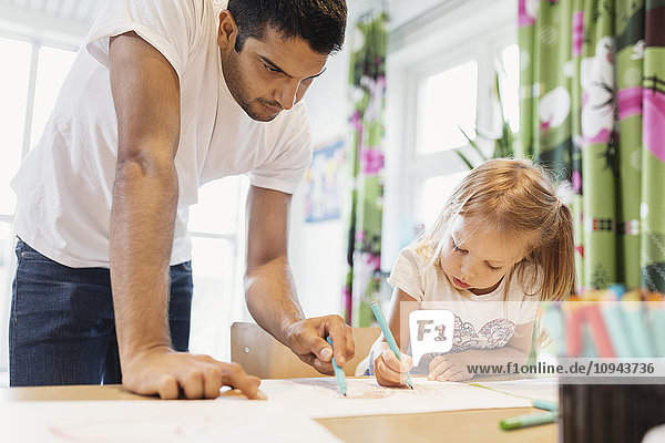 Männliche Kinder  die dem kleinen Mädchen beim Zeichnen im Klassenzimmer helfen.