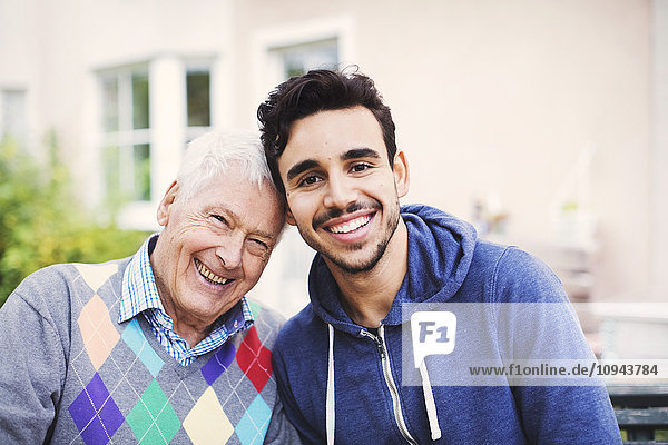 Porträt eines glücklichen älteren Mannes mit Hausmeister  der im Freien sitzt
