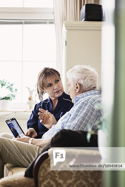 Älterer Mann im Gespräch mit dem Hausmeister bei der Benutzung des digitalen Tabletts im Pflegeheim