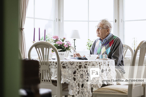 Thoughtful senior man sitting on dining table at nursing home