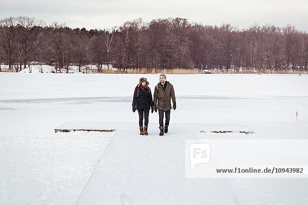 Couple walking on snow covered landscape