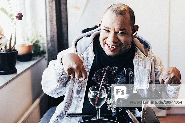 Portrait of happy disabled man with drink at recording studio