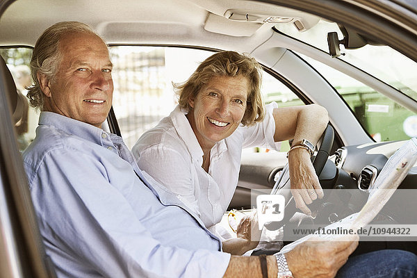 Porträt eines im Auto sitzenden Paares mit Straßenkarte