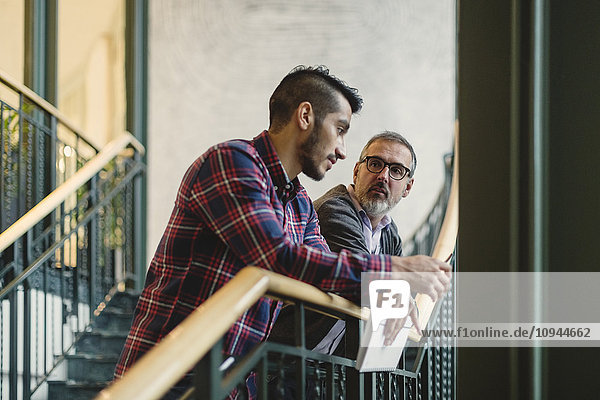 Mature businessman discussing with coworker on staircase in office