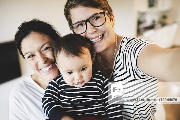 Porträt eines lächelnden lesbischen Paares mit Kleinkind zu Hause