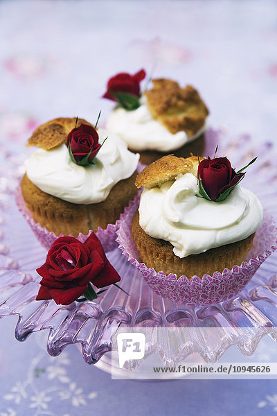 Drei Cupcakes mit Schlagsahne und Rosen