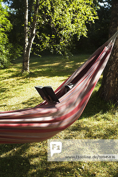 Mature man relaxing in hammock and reading book