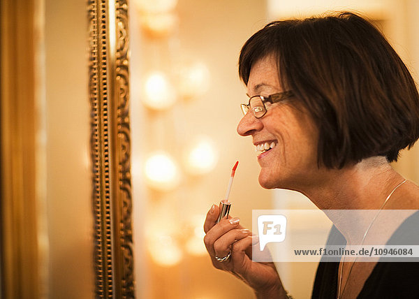 Mature woman applying lipstick  smiling