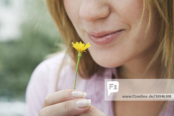 Nahaufnahme einer Frau  die an einer gelben Blume riecht