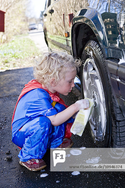 Girl wiping rim of car wheel