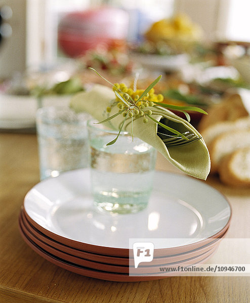 Stapel von Tellern  Gläsern und Blumen auf dem Tisch