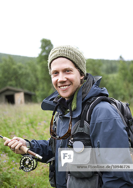 Portrait of smiling mid adult man with fishing rod