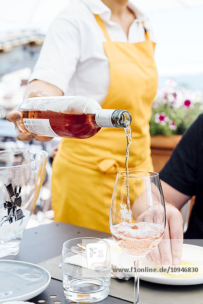 Kellnerin gießt Wein in Weingläser ein
