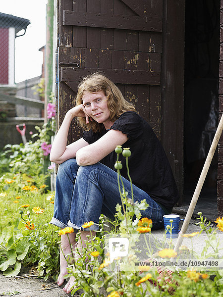Mid adult woman sitting in barn door