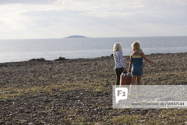 Zwei Mädchen tragen Tasche am Strand