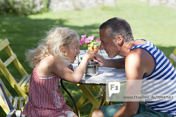 Father and daughter eating together from one saucepan