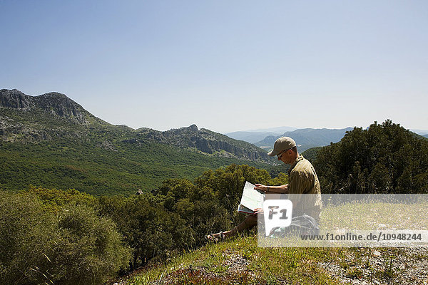 Man sitting with map on top of hill