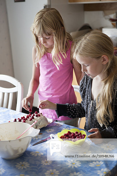 Two girls preparing cake in kitchen