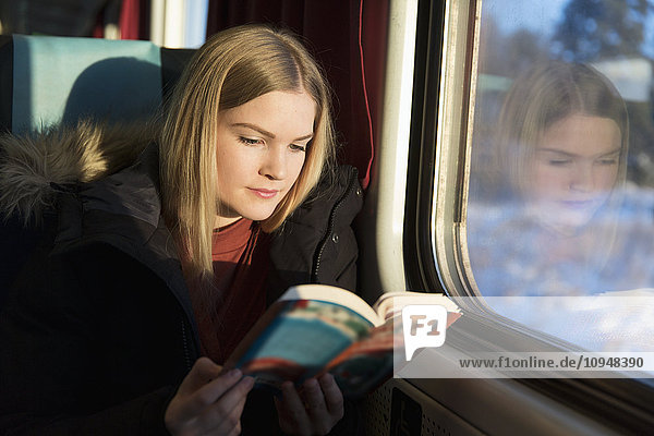 Young woman reading book in train
