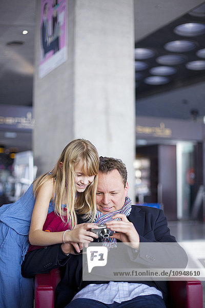 Girl with father looking at digital camera